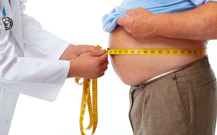 Persona midiendo su cintura con una cinta métrica como indicador de salud cardiovascular.